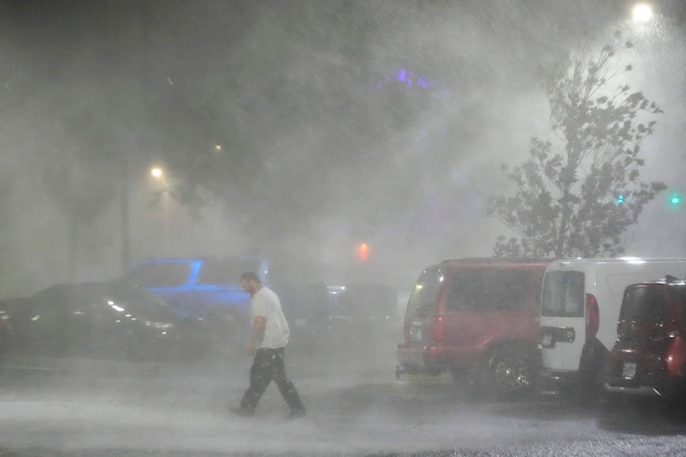 Max Watts, of Buford, Ga., walks in the parking lot to check on a trailer parked outside the hotel where he is riding out Hurricane Milton with coworkers, Wednesday, Oct. 9, 2024 (AP)